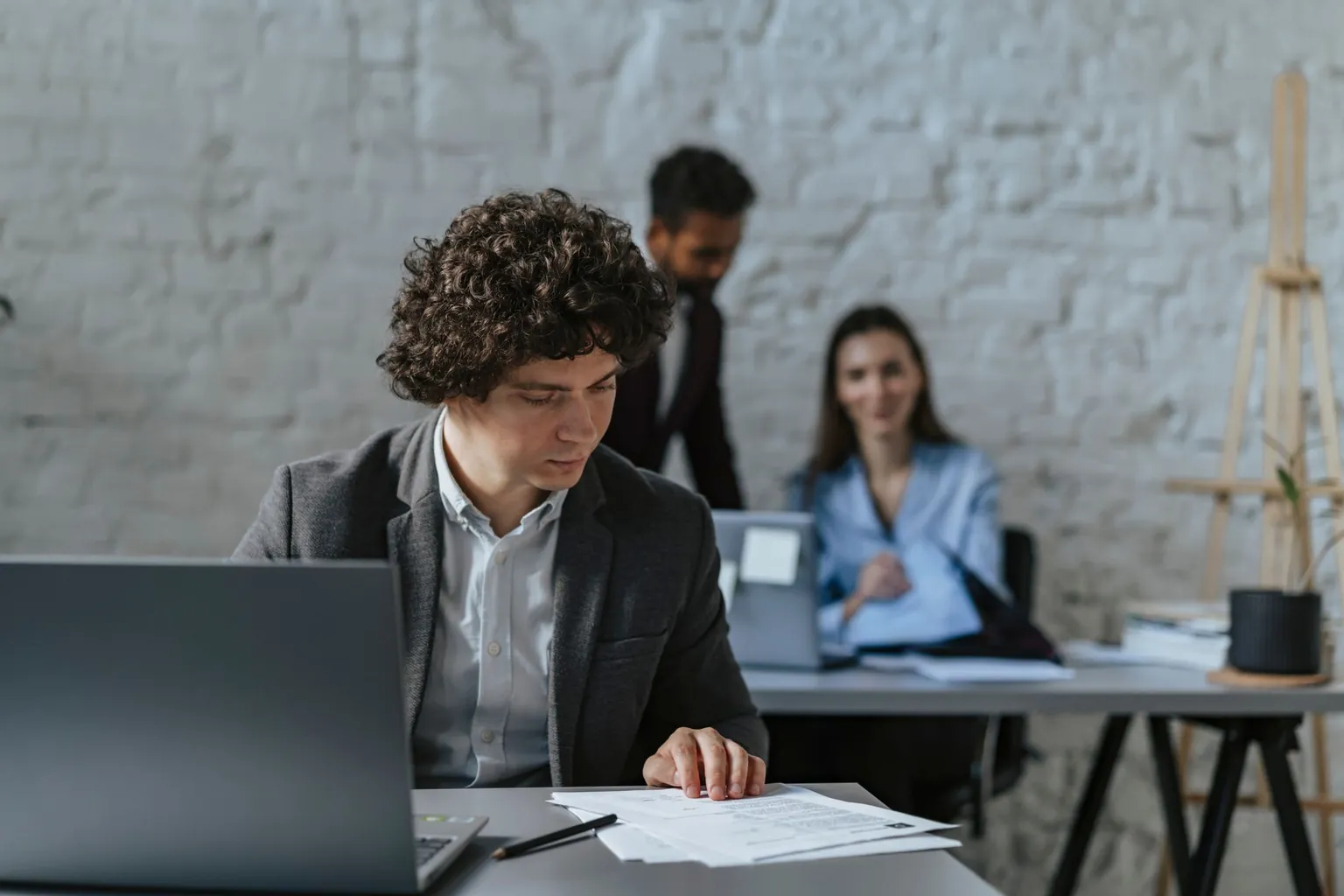 Homme qui relit des documents papier à son bureau, à côté d'un ordinateur portable