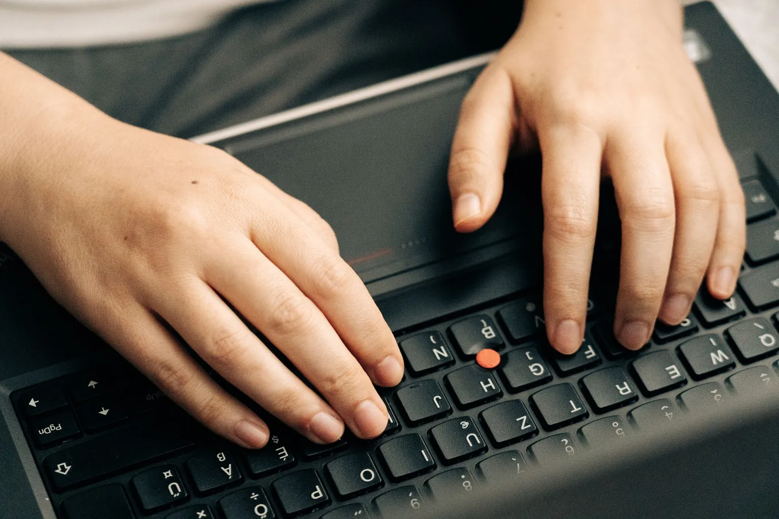 Deux mains posées sur le clavier d'un ordinateur portable noir